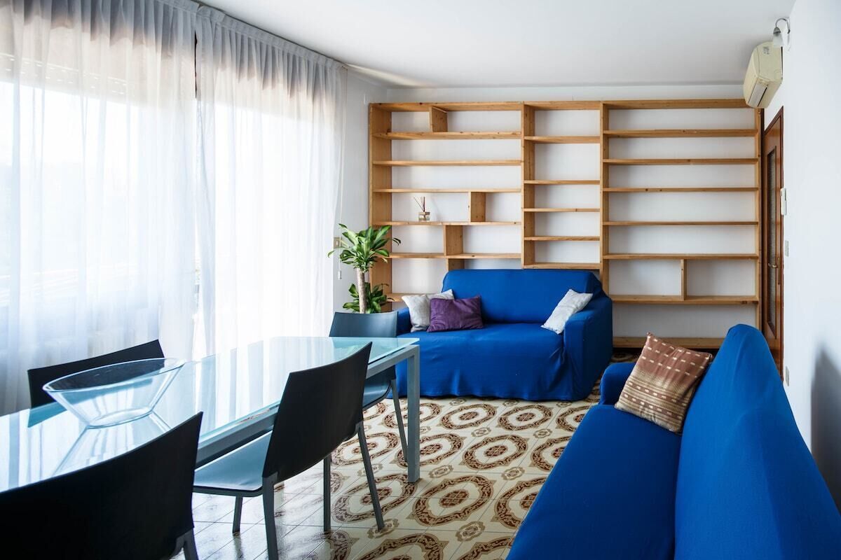 Ein modernes Wohnzimmer mit einem Glastisch, einem blauen Sofa und einer Holzkonsol.