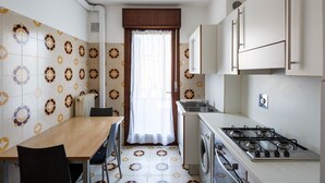 Une cuisine compacte comprenant un coin repas, un lave-linge et une cuisinière.