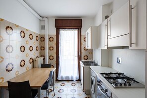 A compact kitchen with a dining area, a washing machine, and a stove.