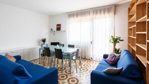 Un salon moderne avec une table à manger, des canapés bleus et un sol à motifs.