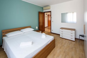 A bedroom with a bed, a dresser, a mirror, and a door leading to another room.