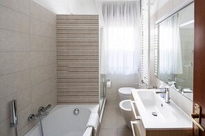 Een bad/douchecombinatie, een haardroger, een bidet, handdoeken