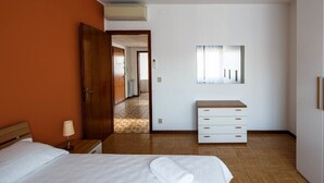 A hotel room with a bed, a nightstand, a dresser, and a mirror.