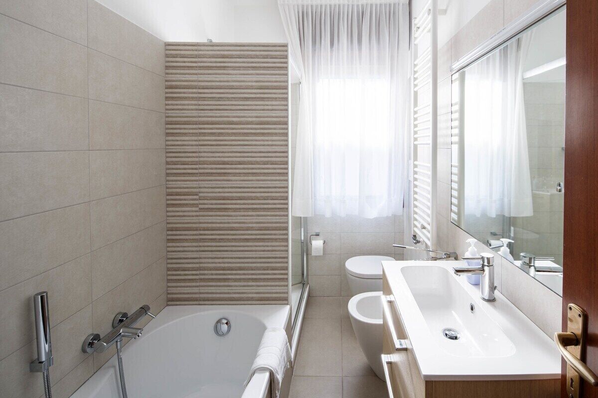 Un baño moderno con bañera, dos lavamanos y un espejo grande.
