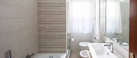 Un baño moderno con bañera, dos lavamanos y un espejo grande.