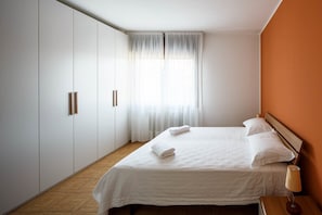 A hotel room with a bed, a nightstand, a lamp, and a window with curtains.