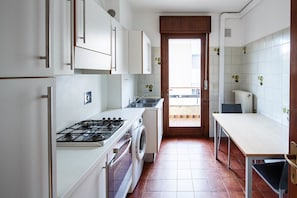 A kitchen with white cabinets, a gas stove, a washing machine, and a sink.