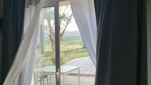 Et værelse med en skydedør, der fører ud til en udendørs terrasse med et bord og stole.