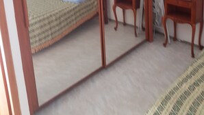 A bedroom with a bed, a bedside table, a mirror, and a wall-mounted picture. - Small apartment 15 minutes from Saint Florent overlooking CAP CORSICA (Santo-Pietro-di-Tenda)