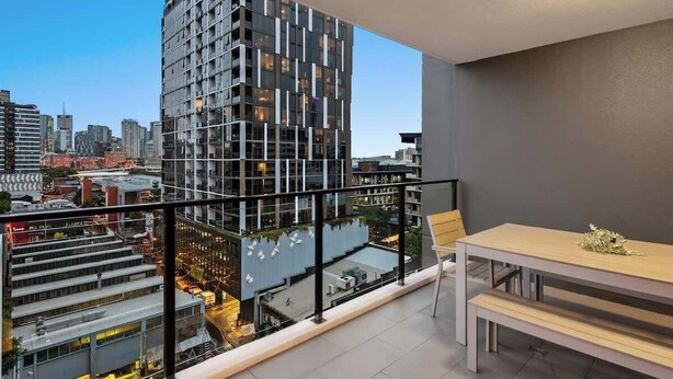 Ein Hochhaus mit modernem Design, ein Balkon mit Tisch und Stühlen sowie ein Blick auf die Stadtlandschaft.