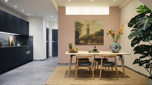 A modern kitchen with dark cabinets, a dining area with a table and chairs, and a large potted plant.