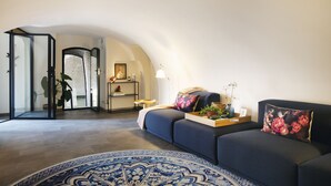 A modern living room with a blue sofa, a patterned rug, and a small side table with a lamp.