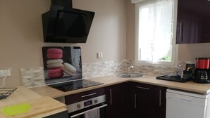 A compact kitchen with a microwave, oven, and dishwasher. There is a window providing natural light and a sink with a faucet. - House 42 m2, 200 m from the sandy beach, with enclosed garden and parking. (Portbail)