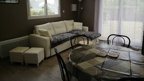 A cozy living area with a sofa, ottomans, a dining table, and chairs. - House 42 m2, 200 m from the sandy beach, with enclosed garden and parking. (Portbail)