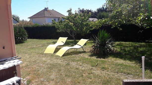 A grassy outdoor area with two yellow lounge chairs, a small plant, and a house in the background. - House 42 m2, 200 m from the sandy beach, with enclosed garden and parking. (Portbail)