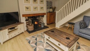 Una sala de estar con chimenea, televisor, sofá y una escalera.