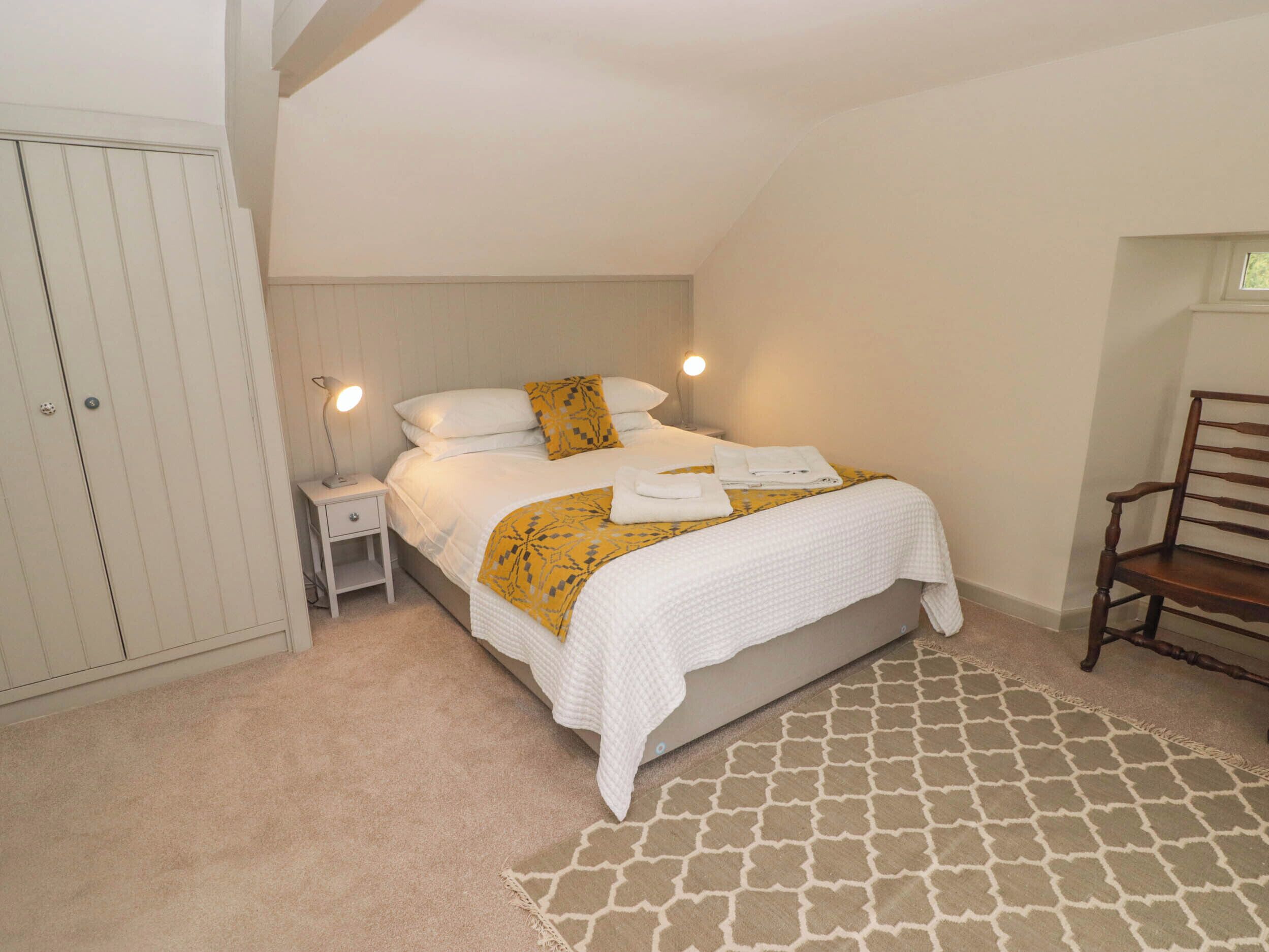 Une chambre à coucher comprenant un lit, des tables de chevet, une armoire et une chaise.