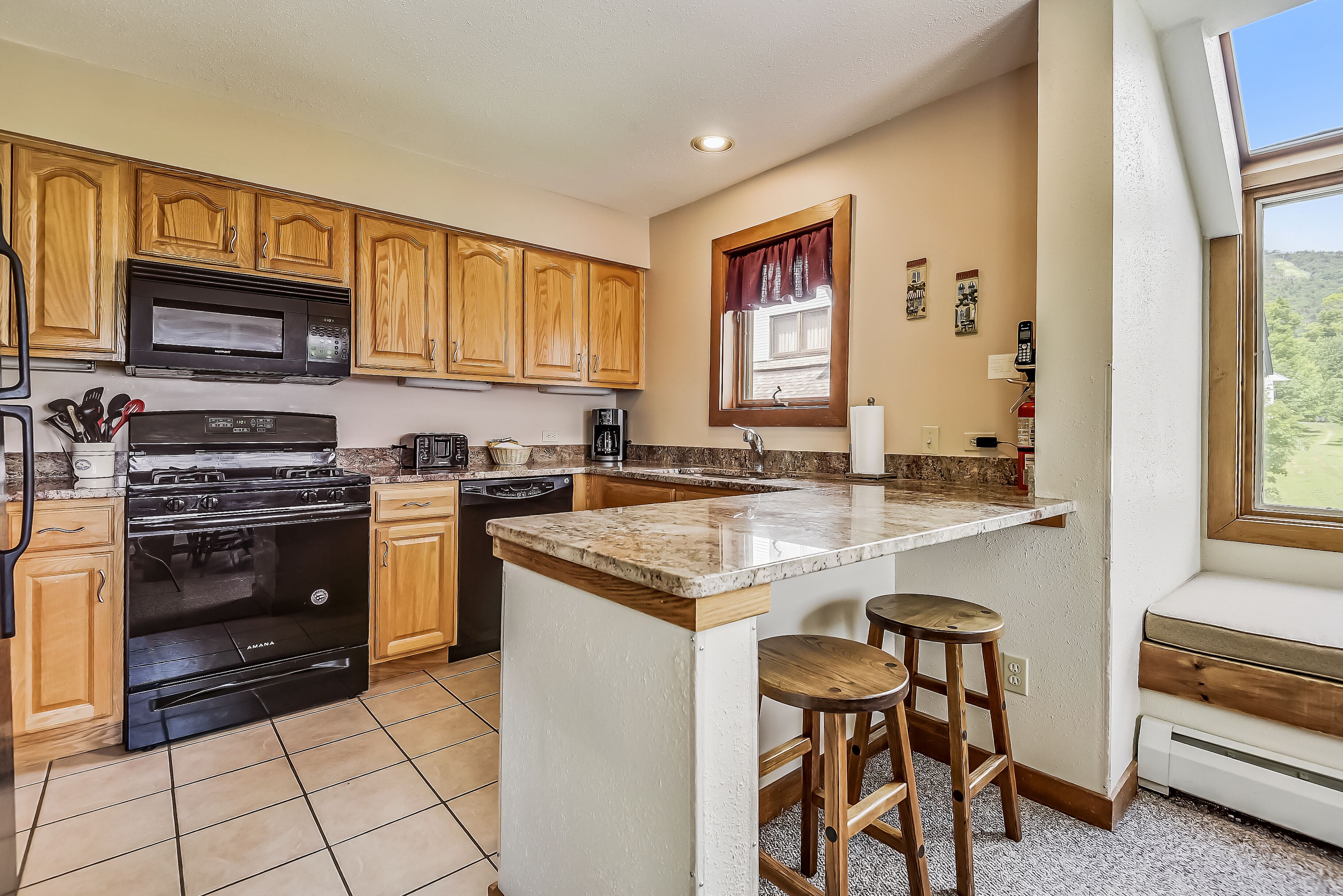 A kitchen with wooden cabinets, a built-in microwave, a stove, and a dishwasher.