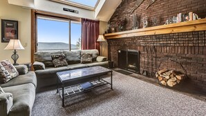 A cozy living room with a fireplace, a sofa set, a coffee table, and a skylight. - Sunrise Timberline K2 fully renovated (Killington)