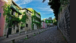 A cobblestone street lined with historic buildings, some with balconies and ivy. - 4-room apartment with 3 bedrooms in Montmartre A/C near the metro (Paris)