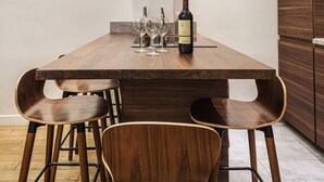 A dining area with a wooden table, four chairs, a wine bottle, and glasses. - 4-room apartment with 3 bedrooms in Montmartre A/C near the metro (Paris)