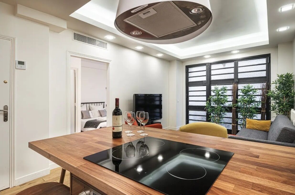 Una cocina moderna con estufa integrada, una mesa de comedor y un televisor.