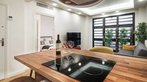 A modern kitchen with a built-in stove, a dining table, and a TV. - 4-room apartment with 3 bedrooms in Montmartre A/C near the metro (Paris)