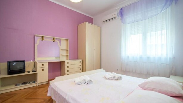 A bedroom with a bed, a TV, a wardrobe, and a window with curtains. - Apartment Jasenka (Split)