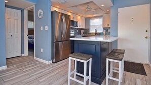 A modern kitchen with a central island, stainless steel appliances, and a ceiling fan.