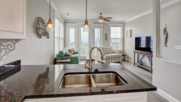 A modern kitchen with a granite countertop, double sink, and a ceiling fan. - 3 Bedroom Townhome in Surf City (Surf City)