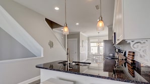 A modern kitchen with a central island, pendant lighting, and a view to the dining area. - 3 Bedroom Townhome in Surf City (Surf City)