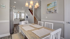 A dining area with a wooden table, white chairs, and a chandelier. - 3 Bedroom Townhome in Surf City (Surf City)