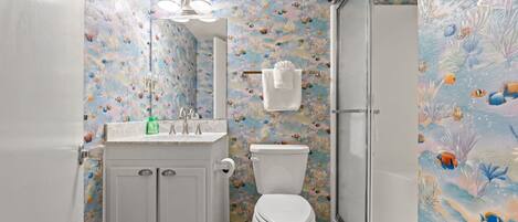 A bathroom with a toilet, sink, and shower.