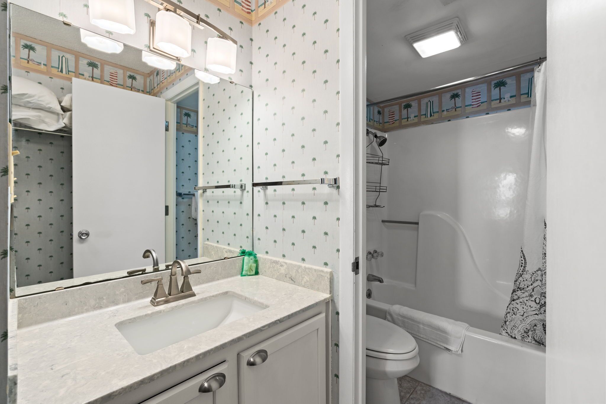 A bathroom with a white sink, mirror, and shower area.