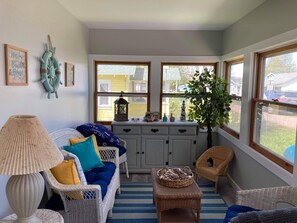 Relax in a cozy room with a comfortable seating area, featuring a wicker sofa and a large window offering a view of the outside.