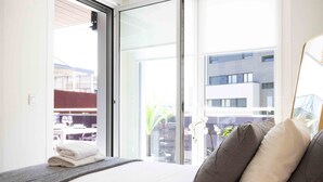 A hotel room with a bed, pillows, a window, and a view of the outside.