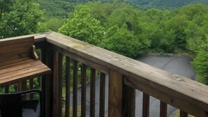 A wooden deck with a view of a lush green valley and distant mountains under a cloudy sky. - The Hideaway at Oma's Meadow (Sugar Mountain)