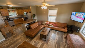 A spacious living room with a sectional sofa, a coffee table, and a TV mounted on the wall. - Fairfield Farm Cottage Dog Horse Welcome EV Charger 1Gig WI-FI Best HOST 21-2023 (Fairhope)