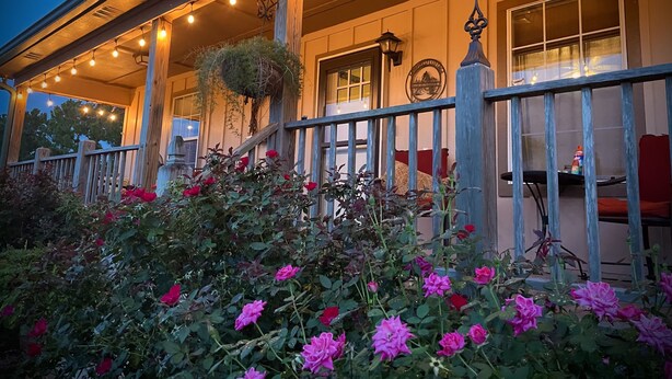 A building with a porch, string lights, and a wooden fence. - Fairfield Farm Cottage Dog Horse Welcome EV Charger 1Gig WI-FI Best HOST 21-2023 (Fairhope)