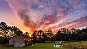 A rural landscape with a house, trees, and a sunset sky. - Fairfield Farm Cottage Dog Horse Welcome EV Charger 1Gig WI-FI Best HOST 21-2023 (Fairhope)