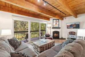 A spacious living room with a fireplace, large windows, and a cozy seating area. - Your Telluride Ski Basecamp | Riverside 2BR | Walk to Slopes, Dining & Downtown (Telluride)