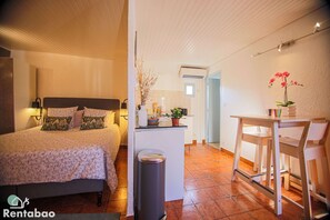 Cozy retreat with a bed, kitchenette, and potted plant.