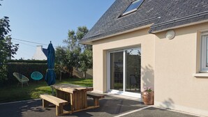 A patio with a wooden table and chairs, a blue umbrella, and a potted plant. - Maison de Vacances Moguériec (Sibiril)