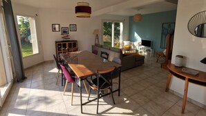 A spacious living area with a dining table, chairs, a sofa, and a TV. - Maison de Vacances Moguériec (Sibiril)