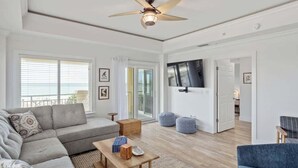 A spacious living room with a grey sectional sofa, a wooden coffee table, and a ceiling fan.