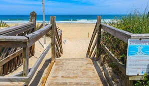A wooden boardwalk leading to a beach with a sign warning about rip currents. - Duck 'N Cover 🏖️Spectacular 4 BR Home w/ Pool, Hot Tub & Easy BEACH ACCESS-🏖️ (Duck)