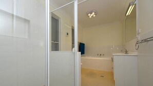 Un bagno moderno con cabina doccia in vetro, vasca e lavandino.
