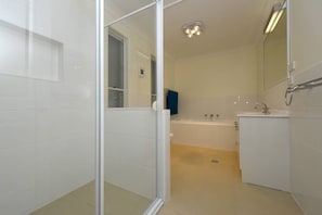 Een moderne badkamer met een douchecabine van glas, een bad en een wastafel.