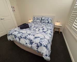 A bedroom with a bed, two bedside tables, a lamp, and a door.