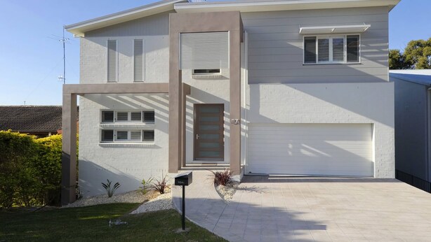 Una moderna casa a due piani con garage, ingresso e cassetta delle lettere.
